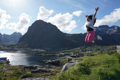 Man standing on rock by mountains against sky