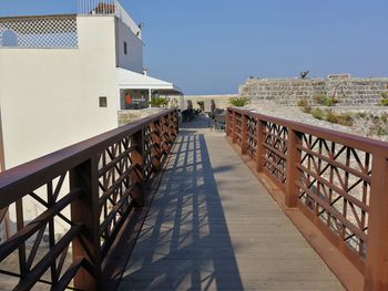 Footbridge amidst buildings against sky