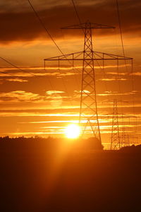 Silhouette electricity pylon against sky during sunset