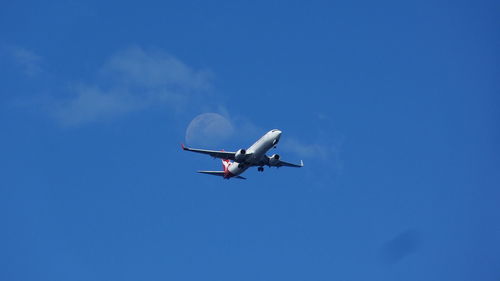 Low angle view of airplane flying against clear blue sky