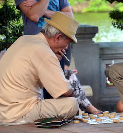 Side view of mature man smoking while playing game outdoors