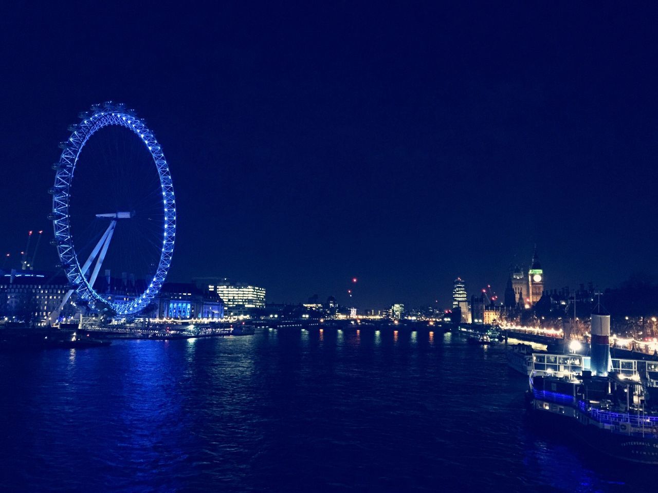 illuminated, ferris wheel, night, waterfront, water, clear sky, copy space, built structure, architecture, blue, building exterior, amusement park ride, nautical vessel, arts culture and entertainment, city, transportation, river, amusement park, sea, travel