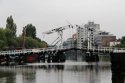 Bridge over river against sky in city