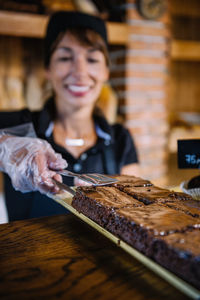 Close-up of smiling young woman preparing brownies at bakery