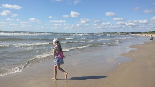 Rear view of person on beach against sky