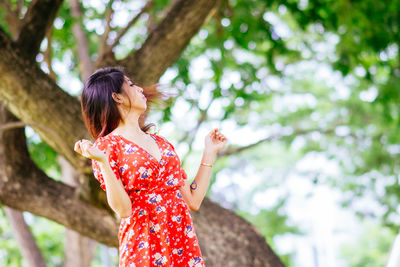 Woman standing by tree trunk