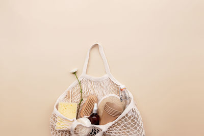 Beige background, eco friendly shopping bag, chamomile flowers, bath accessories, glass bottle, soap