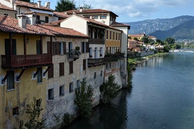 Buildings by river against sky in town