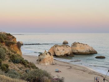 Rocks on beach against sky during sunset