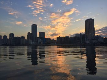 Reflection of city on water at sunset