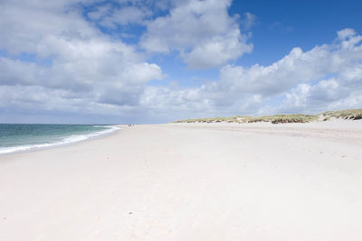 Scenic view of beach against cloudy sky