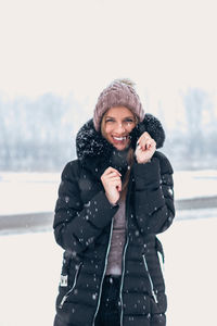 Young woman wearing hat standing against snow during winter