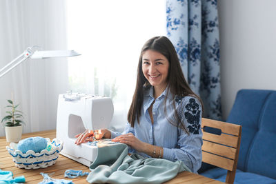 Caucasian girl with long dark hair sews on a sewing machine. concept small business and creativity. 