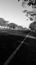 Empty road along trees and against sky