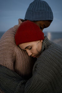 Young woman embracing friend while standing outdoors