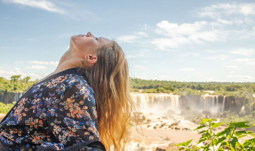 Side view of woman looking at waterfall