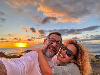 Portrait of young friends on field against sky during sunset