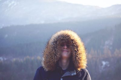 Woman in fur coat against mountains during winter