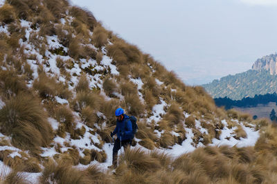 Rear view of man walking on snow covered mountain