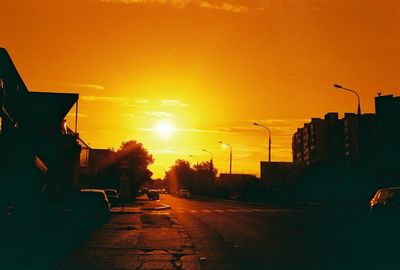 Empty road along buildings at sunset