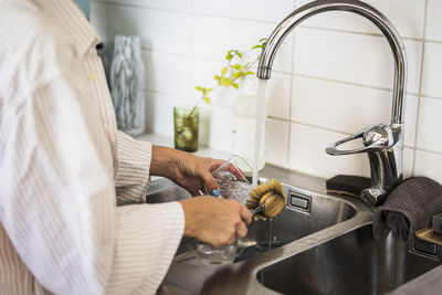 Woman washing dishes in kitchen sink