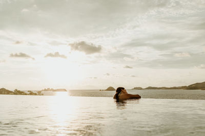 Rear view of woman swimming in sea against sky