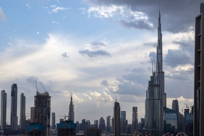 Buildings in city against cloudy sky