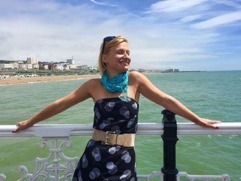 Young woman standing by sea against sky