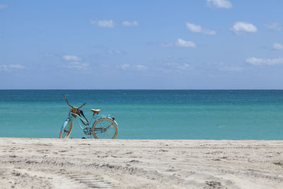 Bicycle on beach against sky