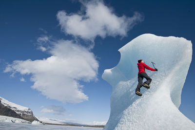 Woman climbinbg iceberg on the fjallsjoull glacier lagoon