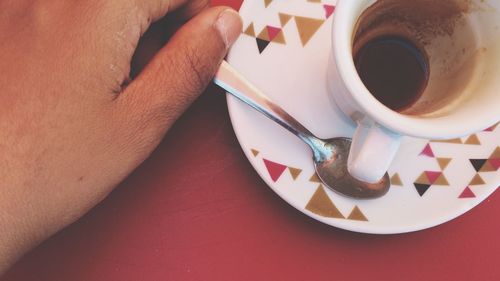 Cropped hand by coffee leftovers on table