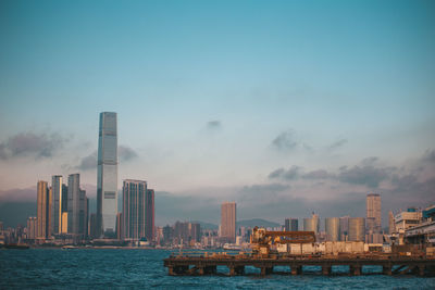 Sea and modern buildings in city against sky in hong kong