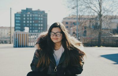 Portrait of young woman standing against city in background