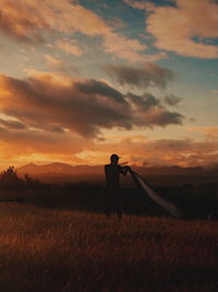 Man working on field against sky during sunset