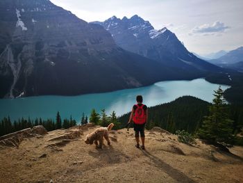 Rear view of man with dog on mountain against sky