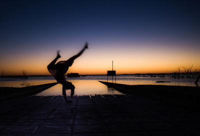 Silhouette woman standing on beach against clear sky during sunset