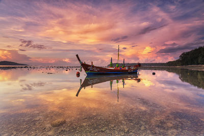 Boats moored in lake against sky during sunset