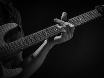 Man playing guitar against black background