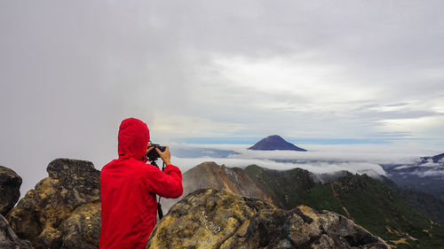 Rear view of woman photographing on mountain