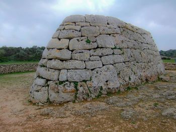 Stone wall on field against sky