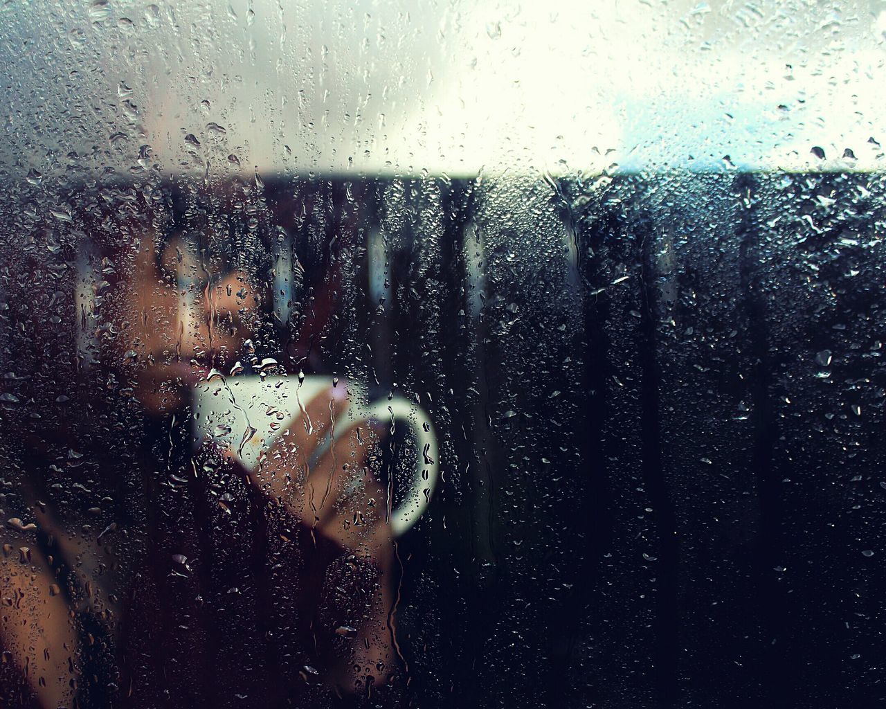 MAN SEEN THROUGH WET WINDOW