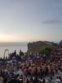 People at beach against sky during sunset