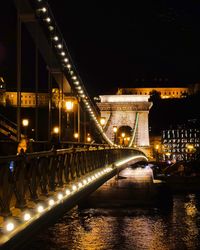 Illuminated bridge over river at night