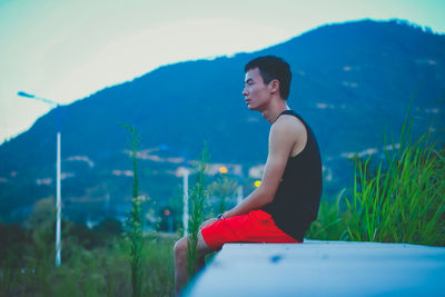 Woman looking away while sitting on mountain