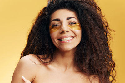 Close-up of young woman against yellow background