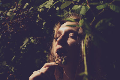 Close-up of woman eating fruit against plants