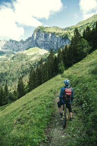 Rear view of man on his mountain bike enjoying the view in the swiss alps.