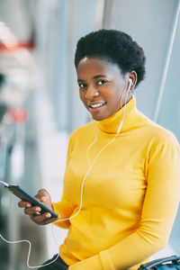 Attractive african girl is waiting for a train in the subway and listening to music with headphones.