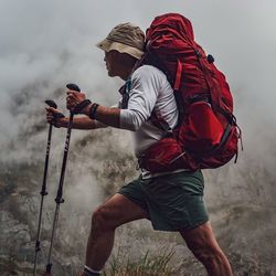 Side view of man holding ice cream against mountain