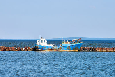 Rusty old abandoned iron fishing boat moored to rusty pier. wrecked weathered fishing trawler